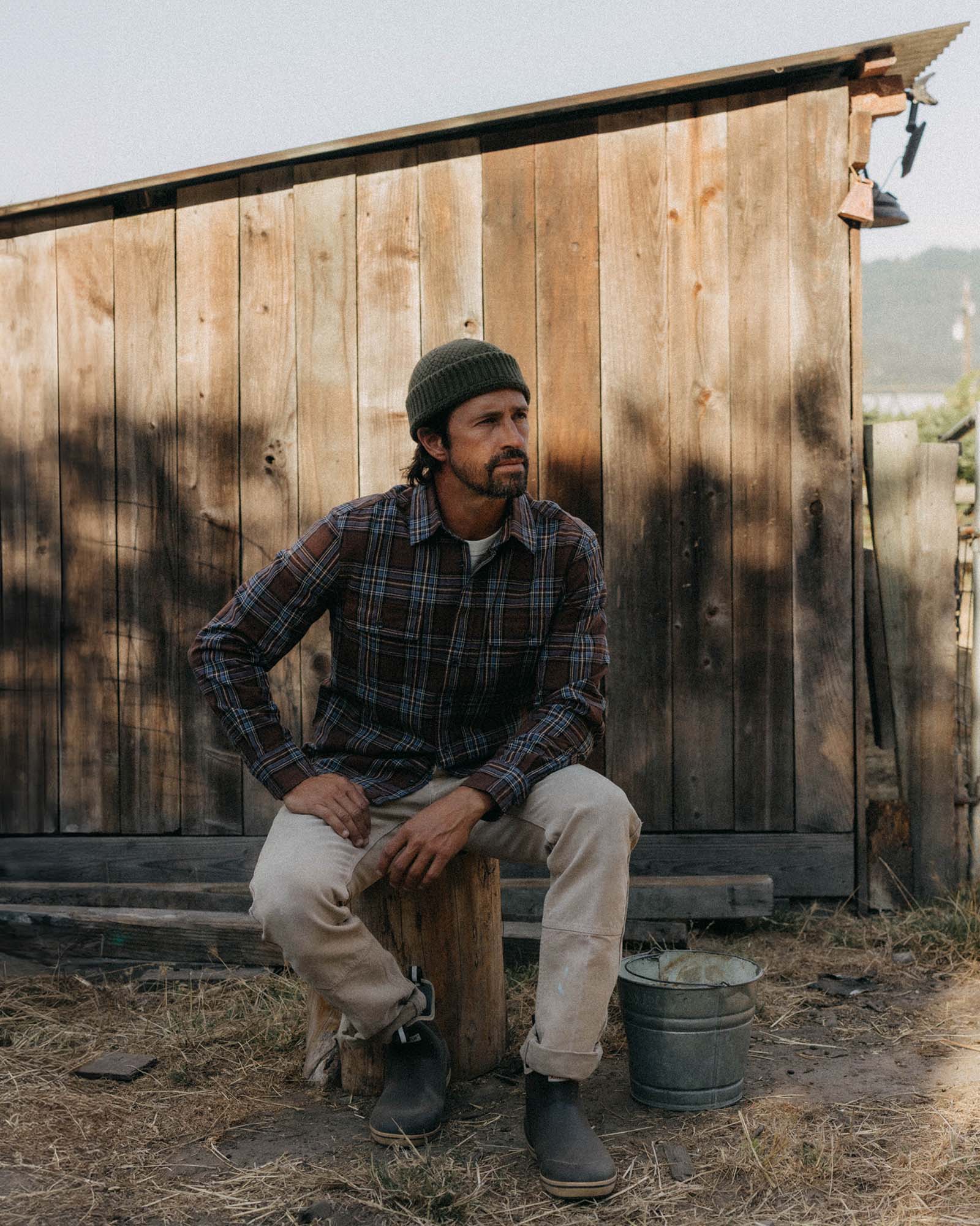 fit model sitting wearing The Craftsman Shirt in Brick Plaid, Wovens by Taylor Stitch