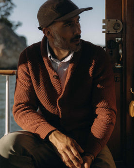 fit model sitting wearing The Crawford Sweater in Rust, Knits by Taylor Stitch