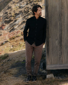 fit model leaning against the wall wearing The Jack in Black Indigo Oxford, Wovens by Taylor Stitch