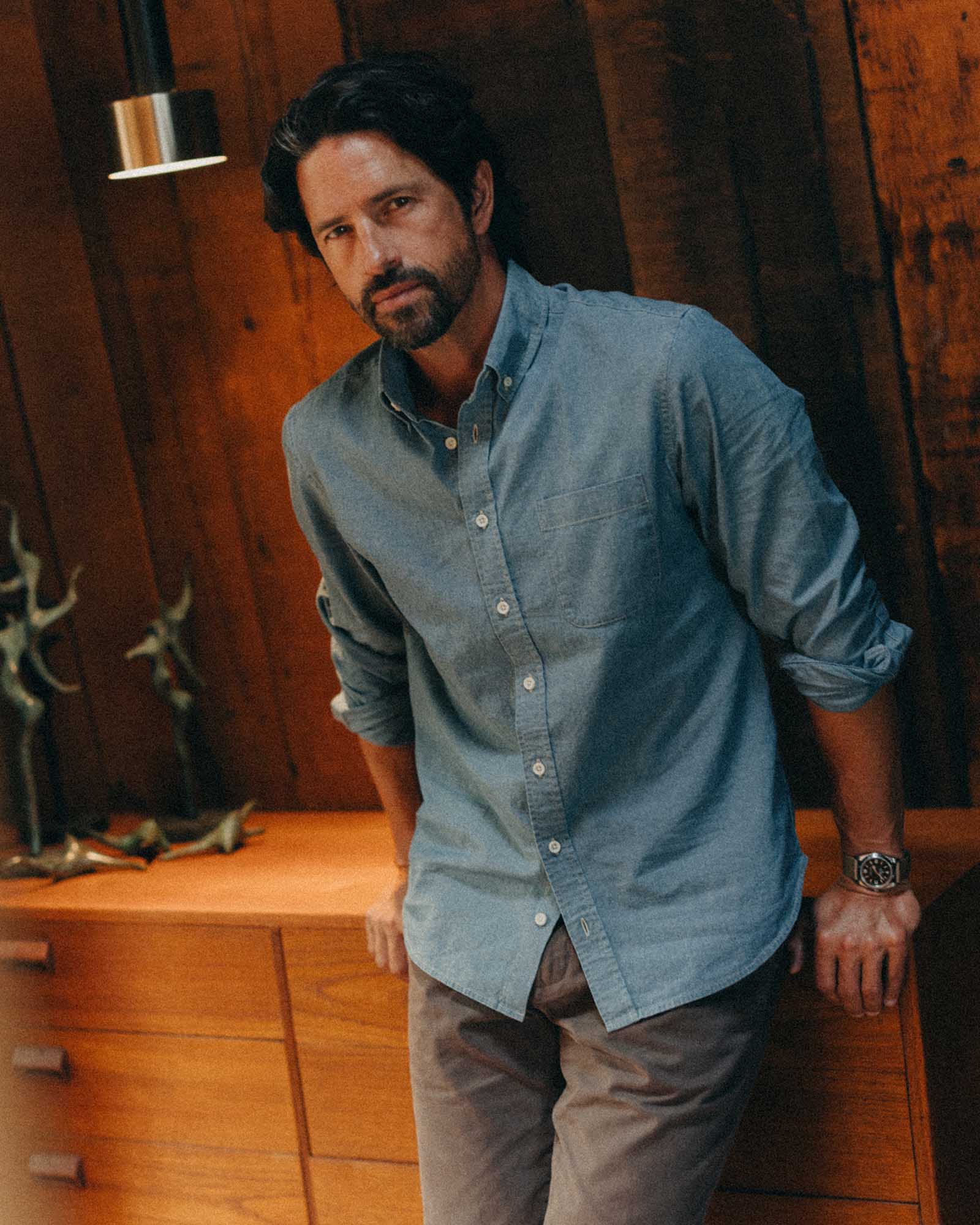 fit model leaning against a dresser wearing The Jack in Washed Indigo Chambray, Wovens by Taylor Stitch