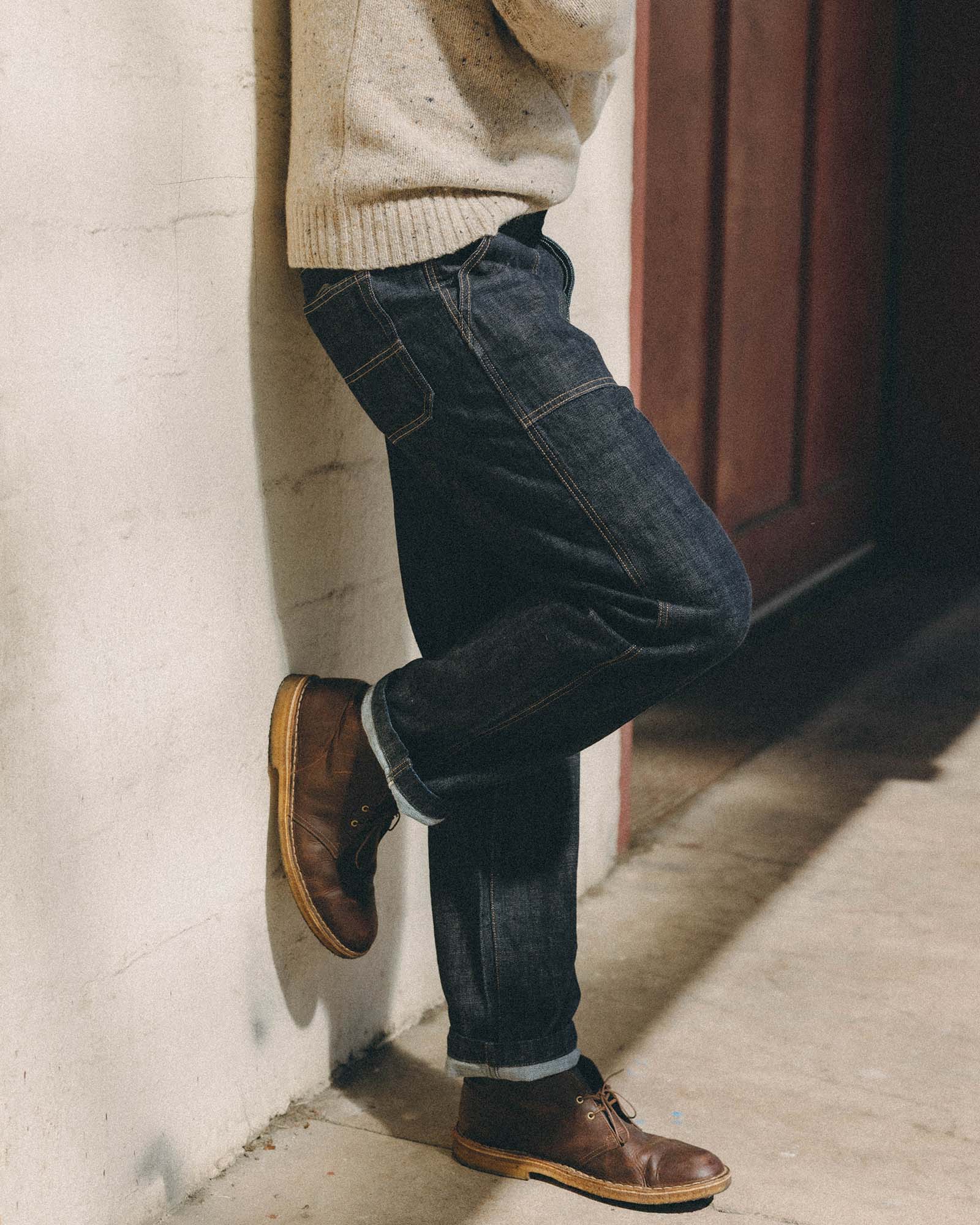 fit model leaning against the wall wearing The Mariner Jean in Rinse Organic Selvedge, Bottoms by Taylor Stitch