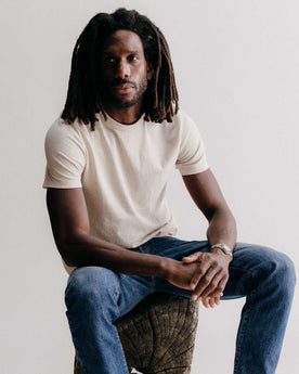 fit model sitting wearing The Organic Cotton Tee in Heather Oat, Knits by Taylor Stitch