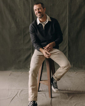 fit model sitting wearing The Rugby Shirt in Coal, Knits by Taylor Stitch