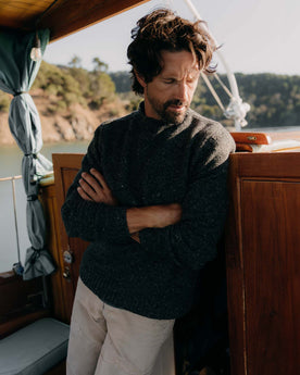 fit model leaning against the wall wearing The Seafarer Sweater in Charcoal Donegal, Knits by Taylor Stitch