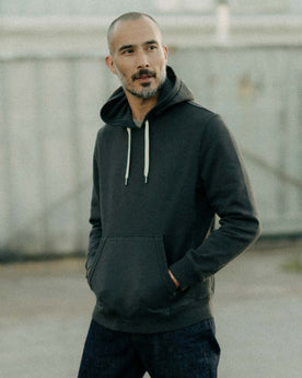 fit model posing in The Shop Hoodie in Faded Black, Knits by Taylor Stitch