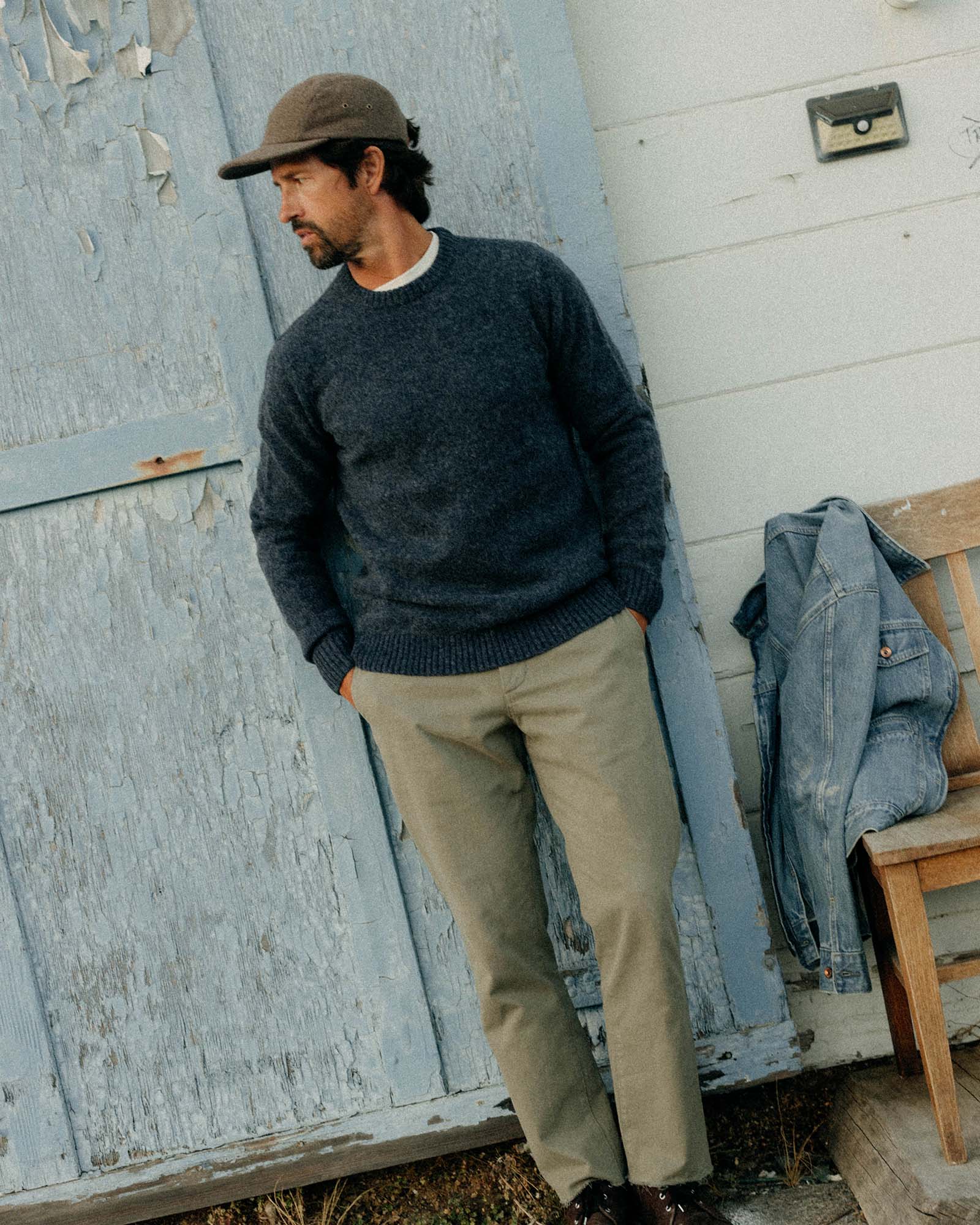 fit model leaning against the wall wearing The Eastmoor Sweater in Heather Night Wool, Knits by Taylor Stitch