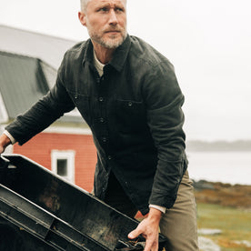 fit model carrying a container in The Lined Utility Shirt in Washed Black Denim