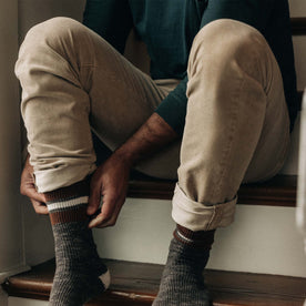 fit model adjusting his socks in The Slim All Day Pant in Light Khaki Cord