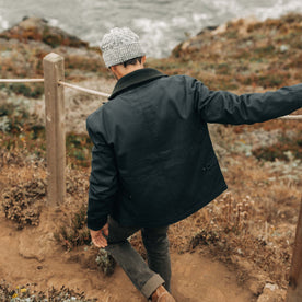 fit model walking down the coast in The Deck Jacket in Dark Navy Dry Wax