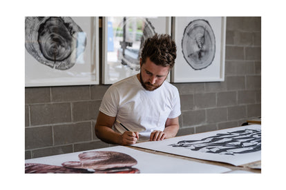 Jack Ludlam signing a print of the American Flag in his studio