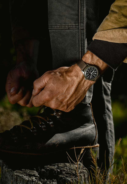 Model tying up his leather boots while wearing the 1991 Timex Camper