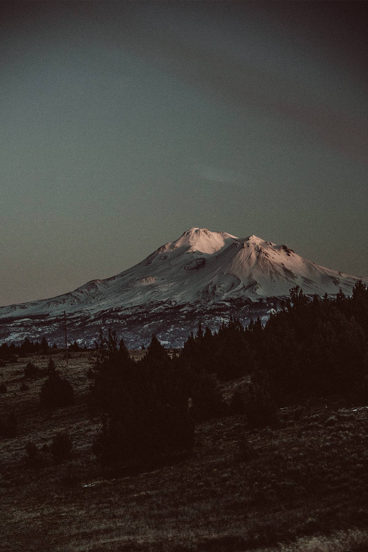 A dark-hued image of a snow-capped mountain.