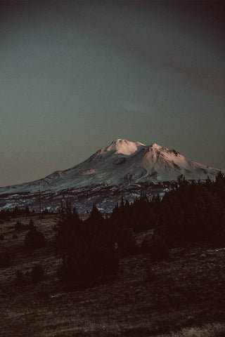 A dark-hued image of a snow-capped mountain.