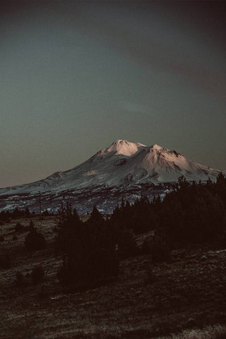 A dark-hued image of a snow-capped mountain.