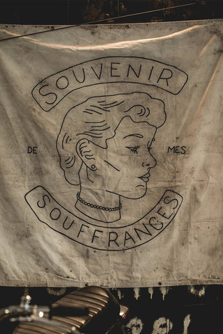 An illustrated face and the words 'Souvenir Sous Frances' printed on white fabric.