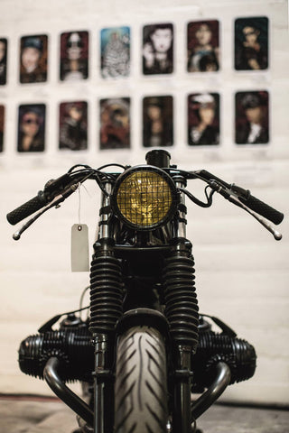 A motorbike front-end, displayed against a wall that has pictures hung on it, but not in focus.
