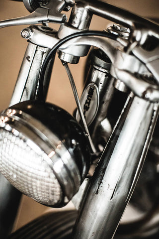 Chrome fork and headlight details on a vintage moto.