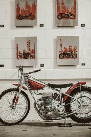 A red motorbike displayed against a wall with severl illustrations of a similarly-colored motorbike.