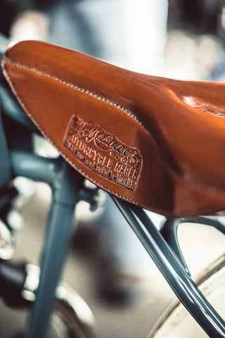 Detail shot of a leather motorbike seat, showing the craftsmans stamp.