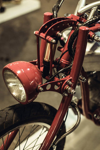 Detail of frame and fork joint and components on a vintage red motorcycle.