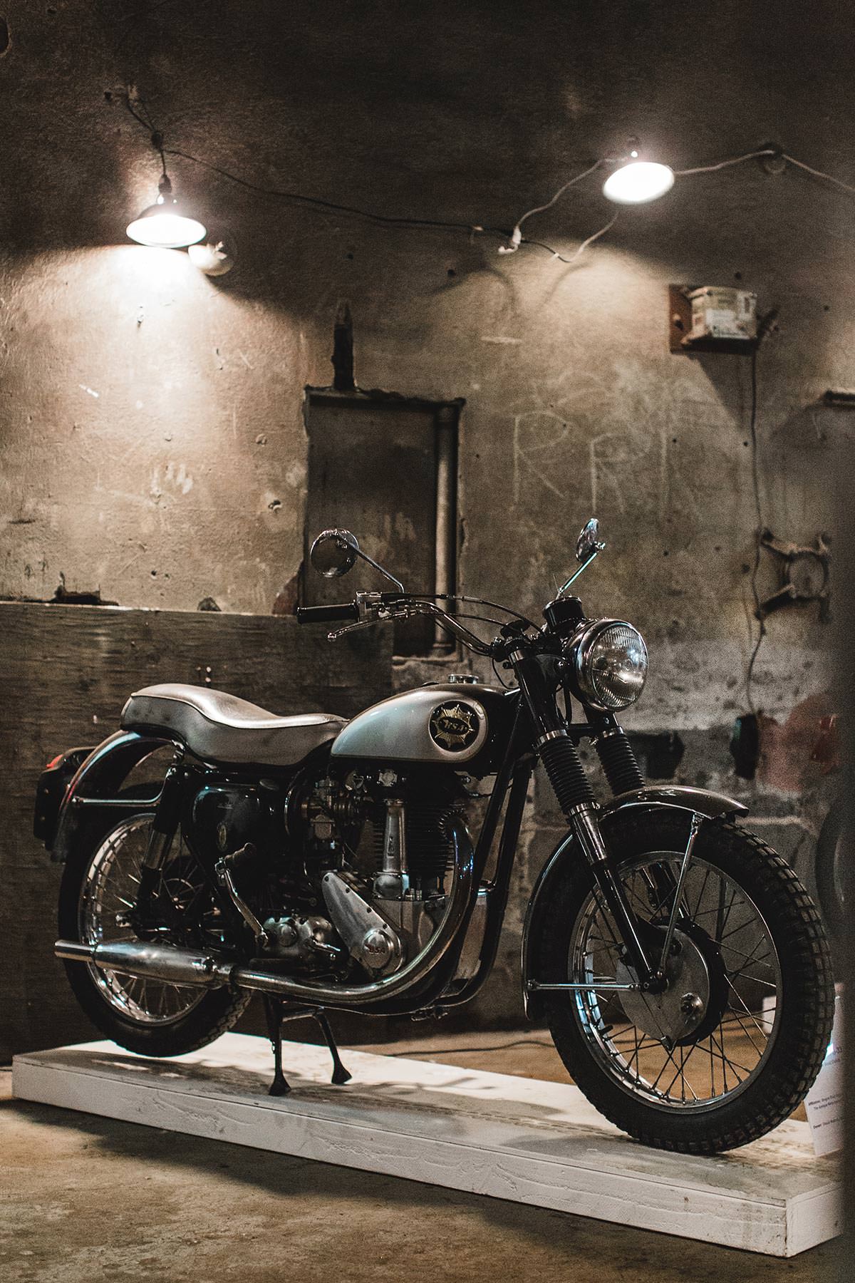 A vintage light blue-painted motorcycle, on display under feature spotlighting.