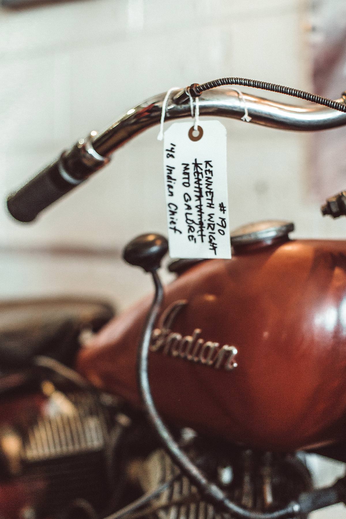 Close-cropped shot of a motorcycle gas tank, with part of a tagged handlebar in the foreground.