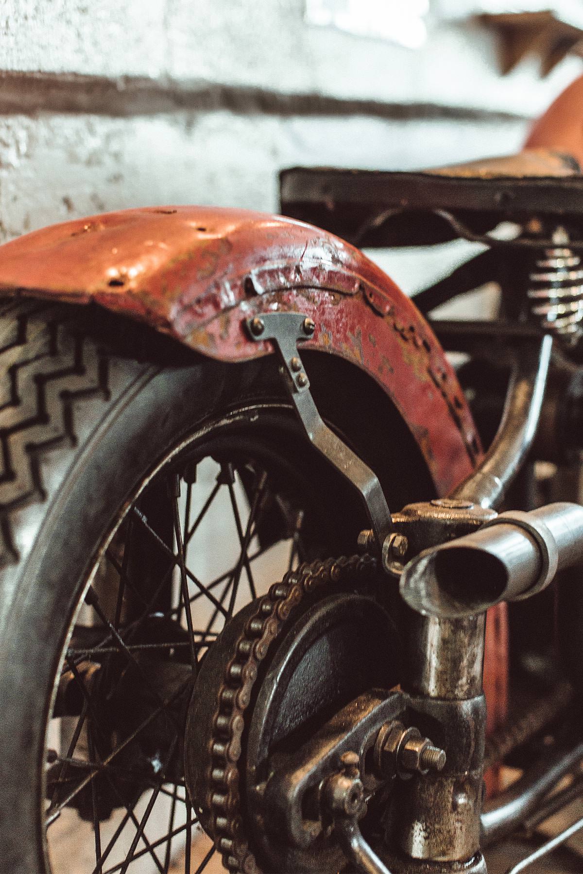 A beat-up red rear fender and motorcycle chain detail.