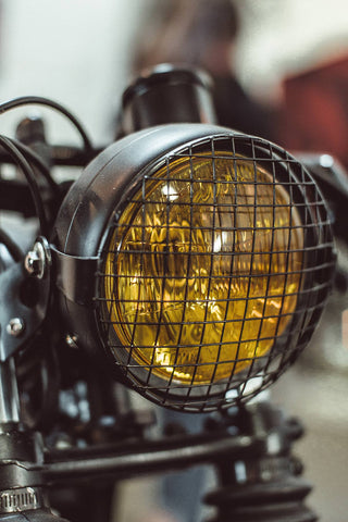 An amber-colored motorcycle headlight and protective grille.