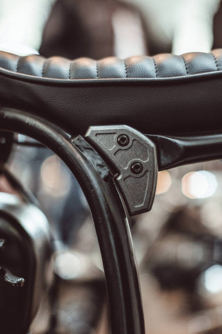 Close-up shot of a leather motorcycle seat and its mounting.