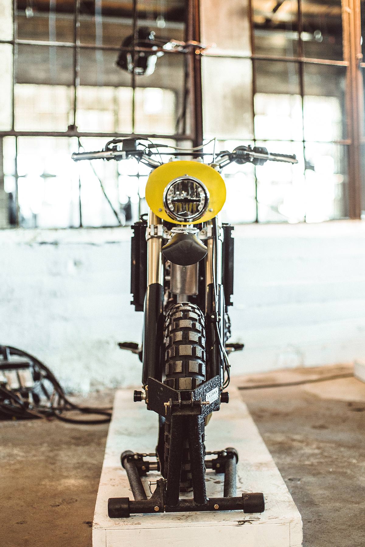Head-on shot of a vintage motorcycle with multi-paned windows in the background.