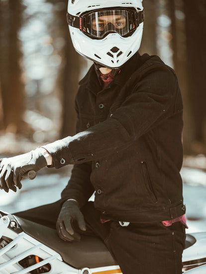 A moto rider facng the camera, paused on a forest trail.