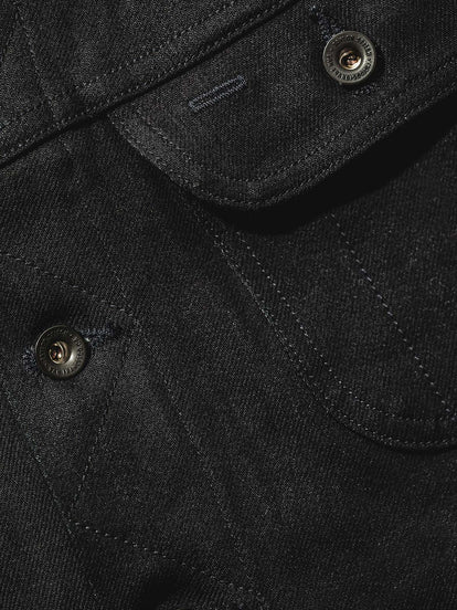 Close up of denim jacket showing pocket and placket stitching detail.
