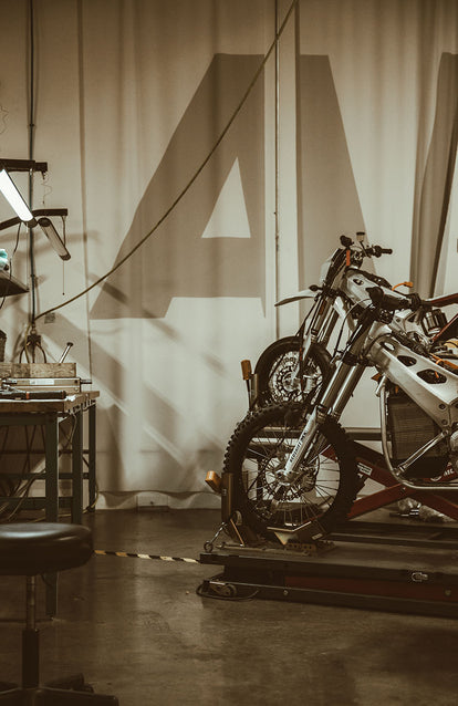 A styled studio set up with two motorbikes and a workbench.