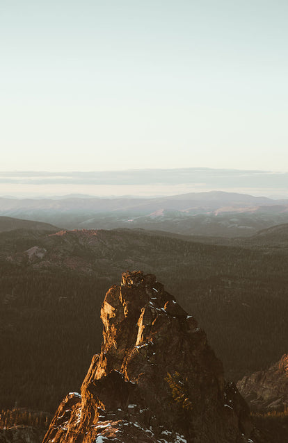 A dramatic rock outcrop with mountain ranges in the distance.