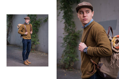 John wearing a backpack, rocking our sweater, walking down a footpath next to a grey wall covered in creeping vines.