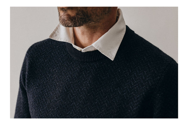 On the left, model wearing The Lodge Sweater, on the right, group of wool sweaters