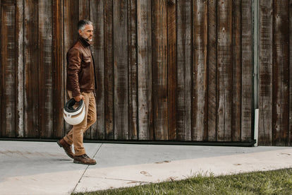 Model walking in front of a barn in The Moto Jacket in Espresso Steerhide
