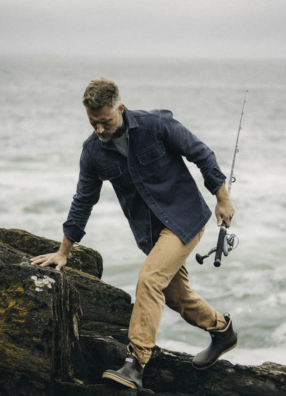 Model walking on the rocks in The Shop Shirt in Navy Chipped Canvas and The All Day Pant in Tobacco Selvage