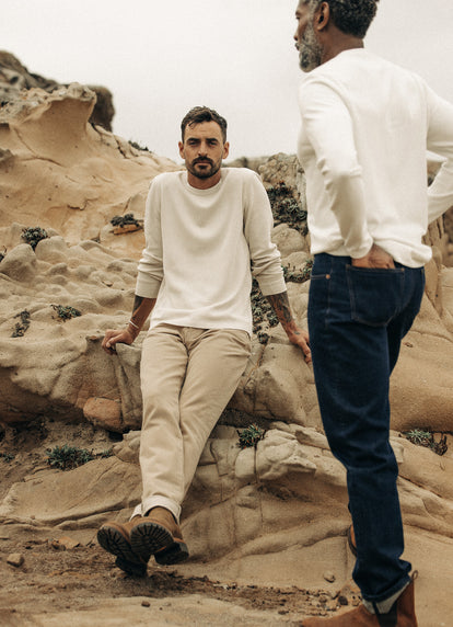 Model sitting on rocks on the beach in The Organic Cotton Waffle Crew and All Day Pant