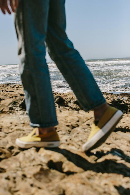 Our guy wearing the gold Sano sneakers at the beach, walking left of camera.