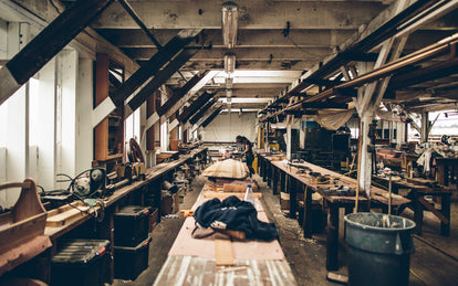 The interior of a workshop, with a craftsman in the background wearing ear-defenders.