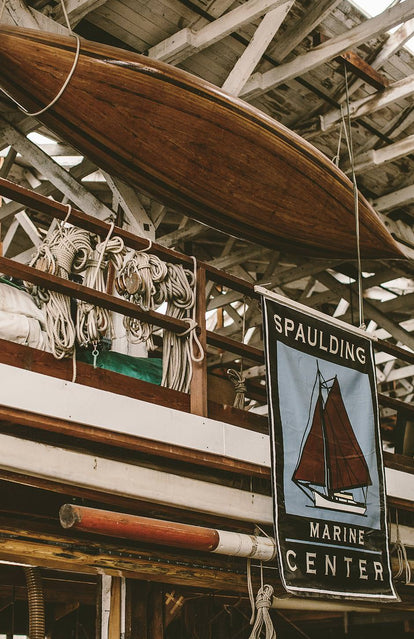 A Spaulding Marine Center sign hanging inside a wooden framed building, hung with marine-related tackle, ropes and a canoe.
