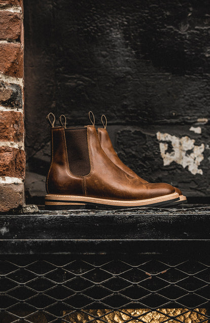 Side shot of a pair of boots against a black-painted brick wall.