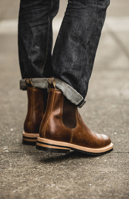 Denim and boot-clad lower legs, walking on concrete.
