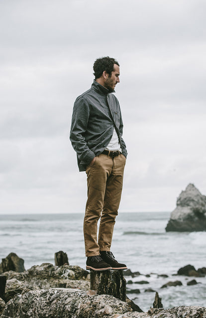 Mikey Armenta standing on a tree stump on the edge of the ocean, looking into the water.