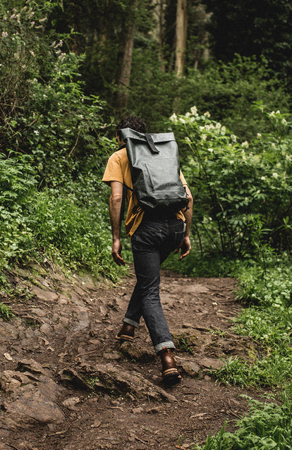Hiking up a muddy forest trail with a waterproof backpack.