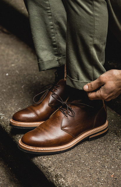 Green chinos getting rolled up over some shiny new boots.