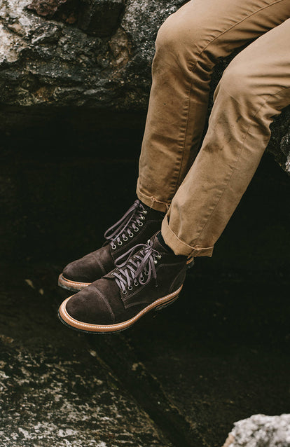 Sitting on a rock, boot-shod legs swinging.
