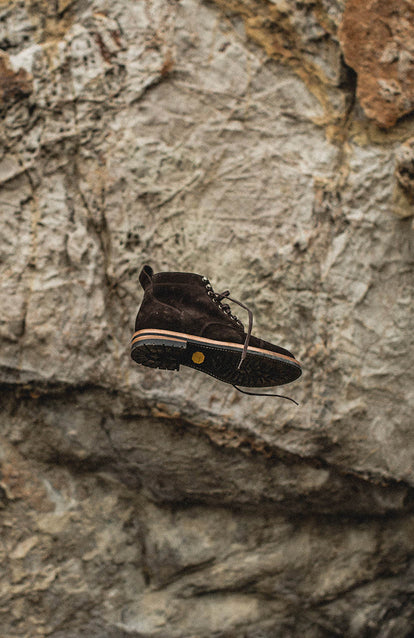 Freeze-frame shot of a boot in mid-air against a rock backdrop.