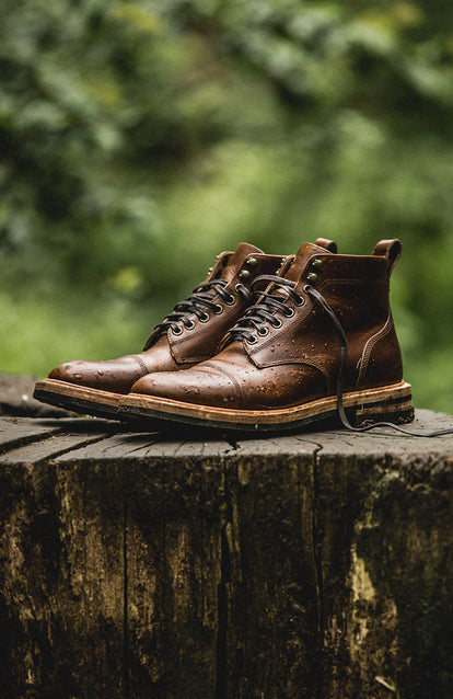 A pair of boots on a tree stump in a wet forest.